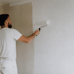 Peintre appliquant peinture blanche sur mur avec rouleau