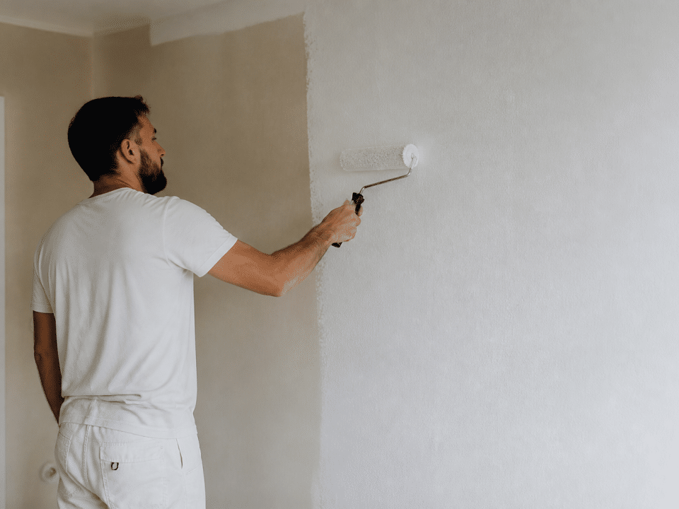 Peintre appliquant peinture blanche sur mur avec rouleau