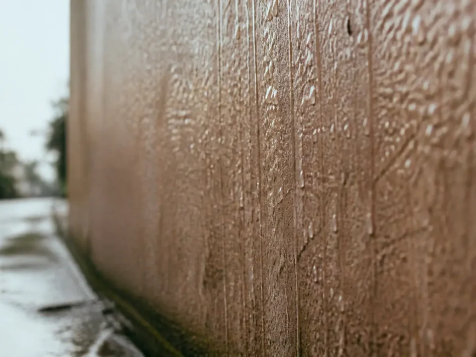 Gouttes d'eau brillantes coulant sur surface murale humide